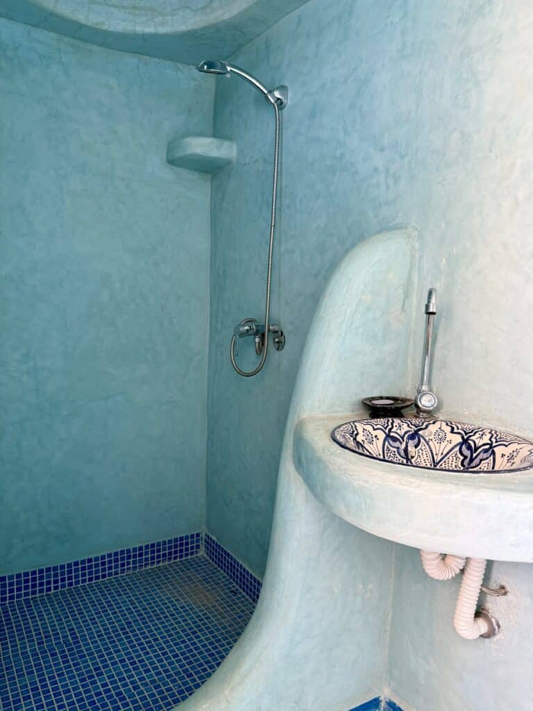baño revestido de tadelakt azul con formas curvas y lavamanos tradicional decorado