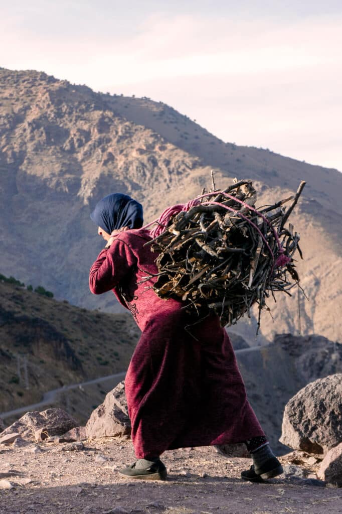 Mujer de espaldas cargando un fardo de leña en las montañas del Atlas, Marruecos
