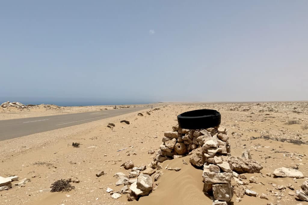 Neumático sobre un montón de piedras junto a la carretera desértica entre El Aaiún y Dakhla, en el Sáhara Occidental