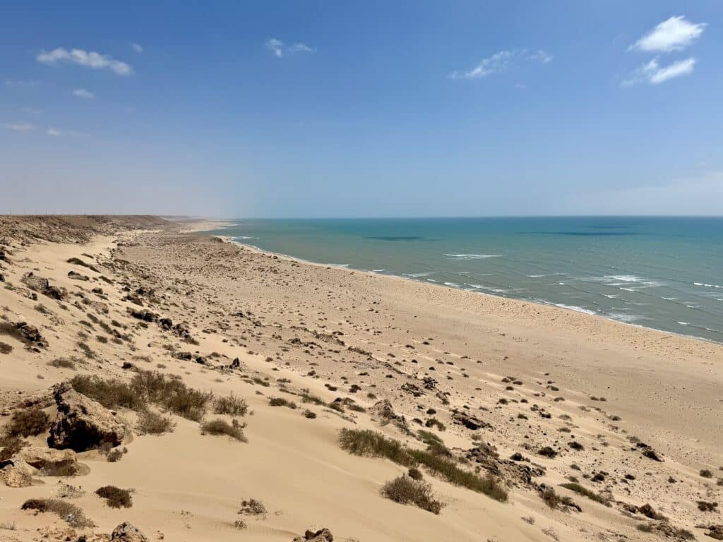 Vista panorámica de la costa atlántica entre El Aaiún y Dakhla, con dunas, arena y mar bajo un cielo despejado