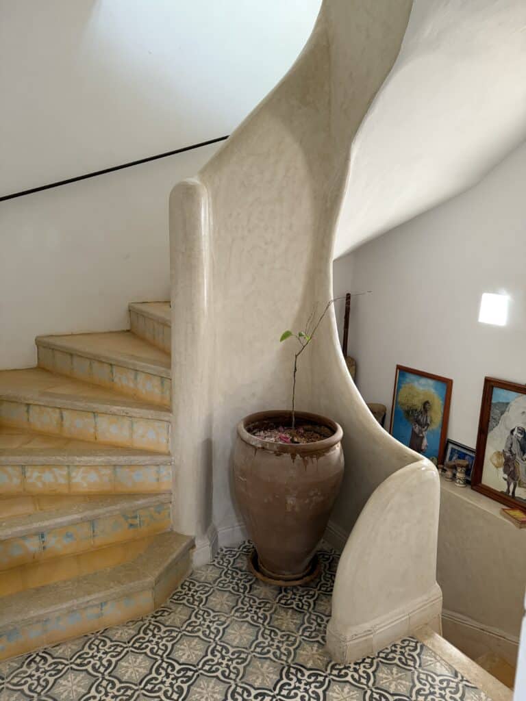 escalera interior revestida de tadelakt beis con detalles artesanales en una casa marroquí