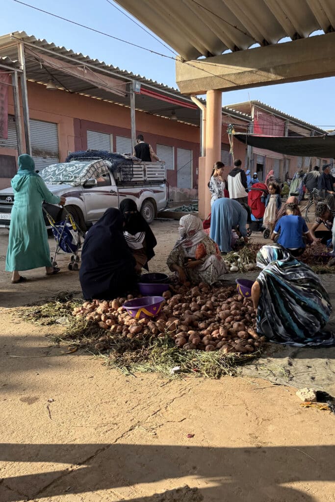 Mujeres sentadas en el mercado de Guelmim; algunas llevan melhfa, una viste niqab negro y otras llevan ropa más urbana