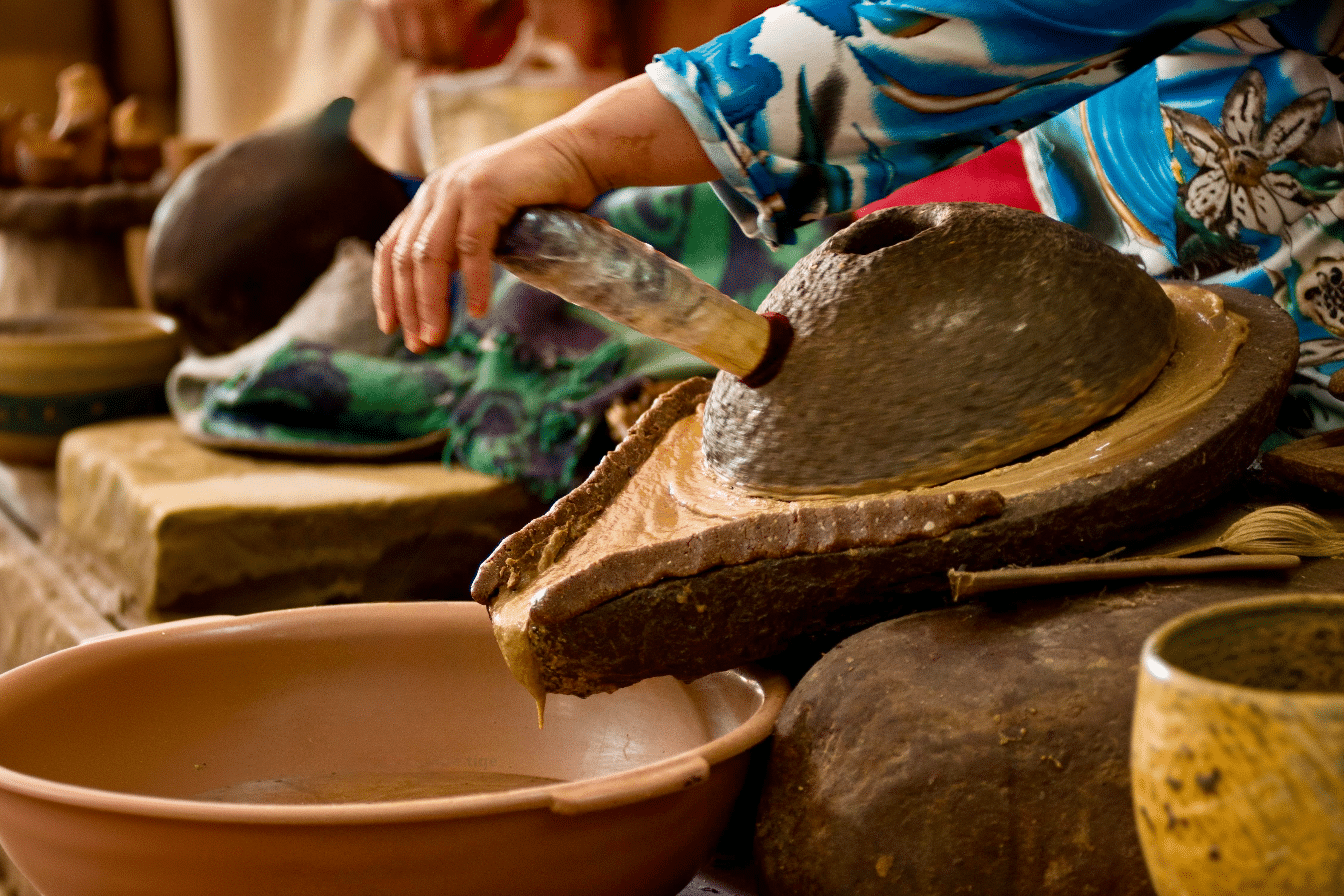 Manos femeninas moliendo nueces de argán con piedras en una cooperativa tradicional