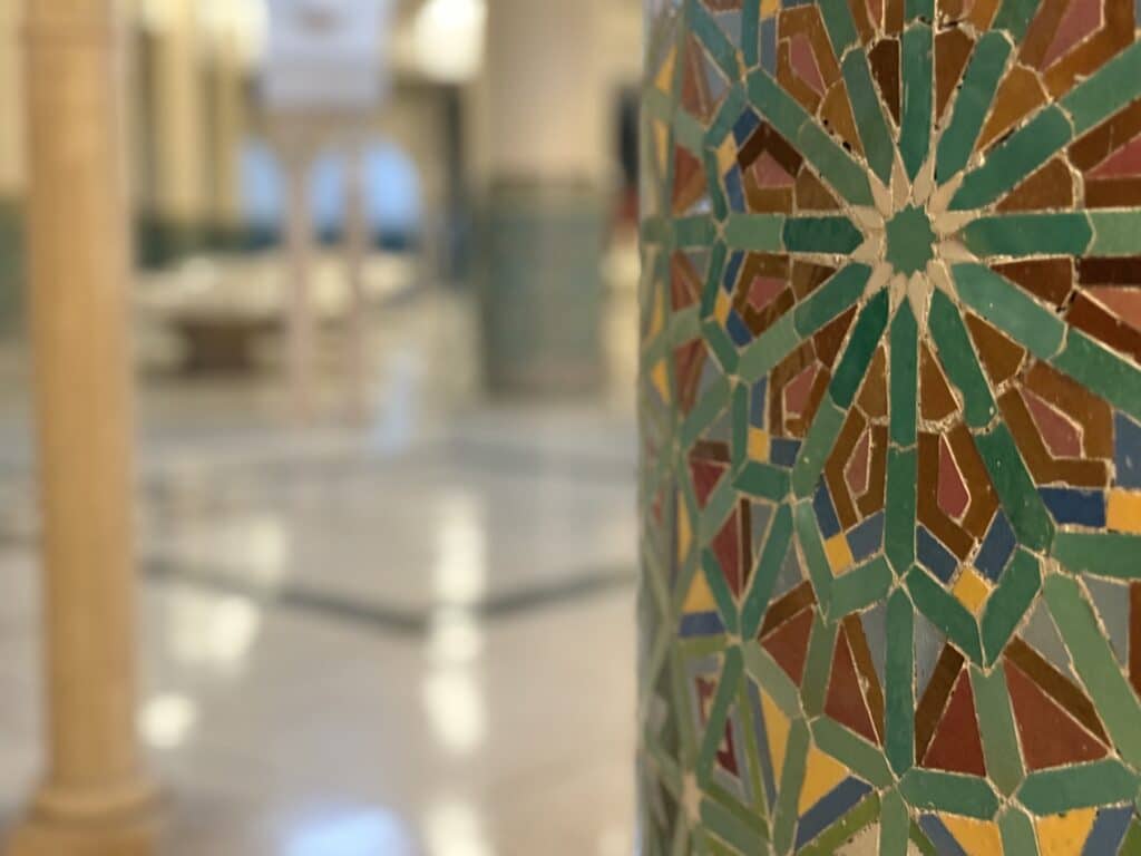 columna revestida con zellige en un edificio tradicional marroquí, mosaicos en tonos verdes y marrones