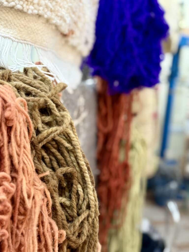 Madejas de lana de distintos colores colgadas en un puesto de trabajo textil artesanal