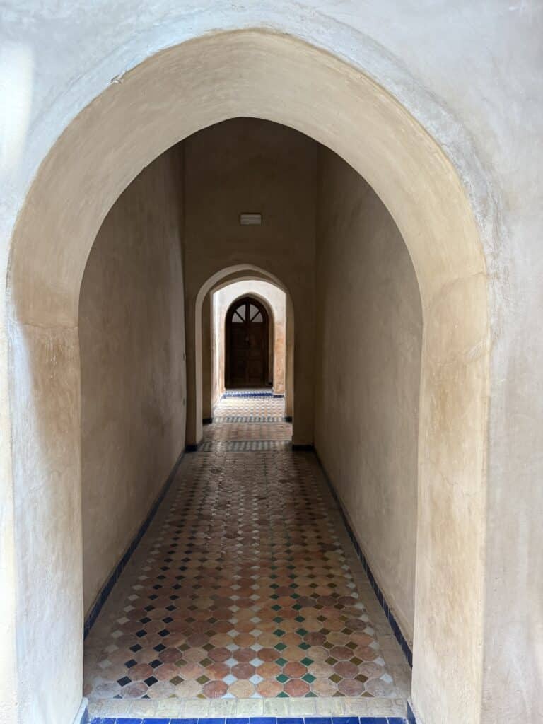 pasillo con arcos y paredes con tadelakt y suelo de zellige en tonos ocres en un edificio tradicional marroquí