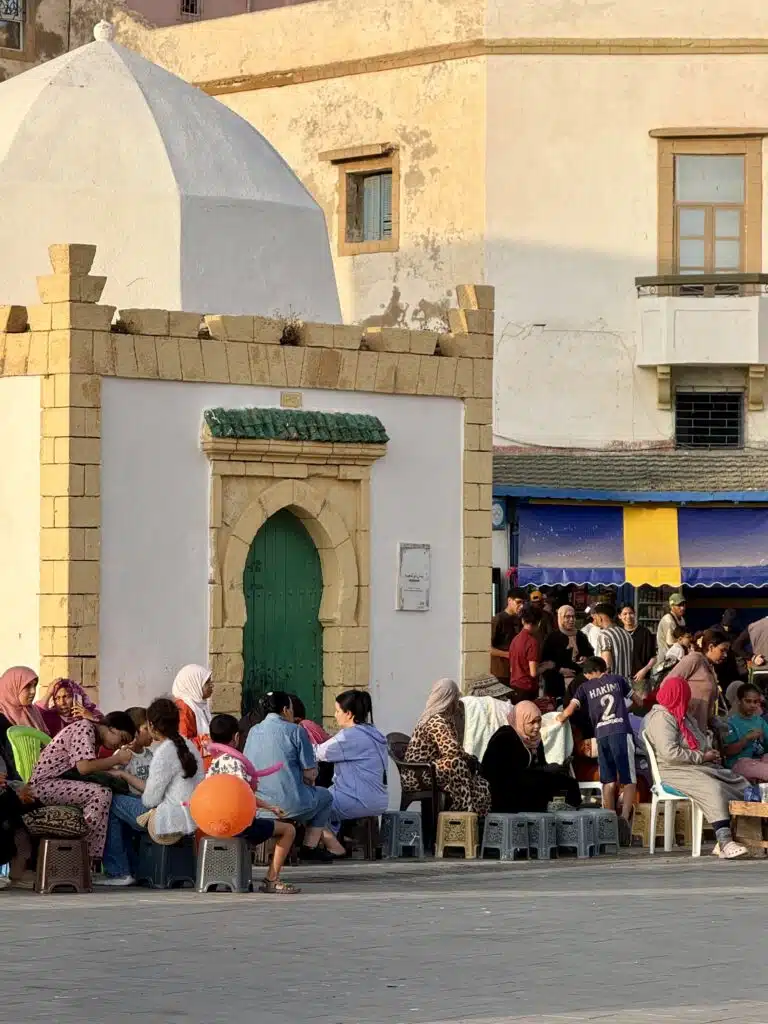 Grupo de mujeres y niñas marroquíes sentadas en la calle pintándose las manos con henna en Essaouira, en la víspera del Eid al-Adha.