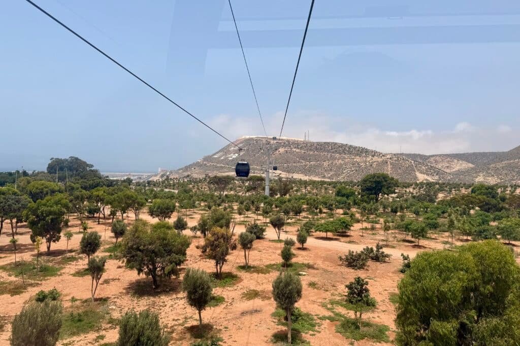 Vista del teleférico que asciende entre árboles hacia la colina de Agadir Oufella en Marruecos