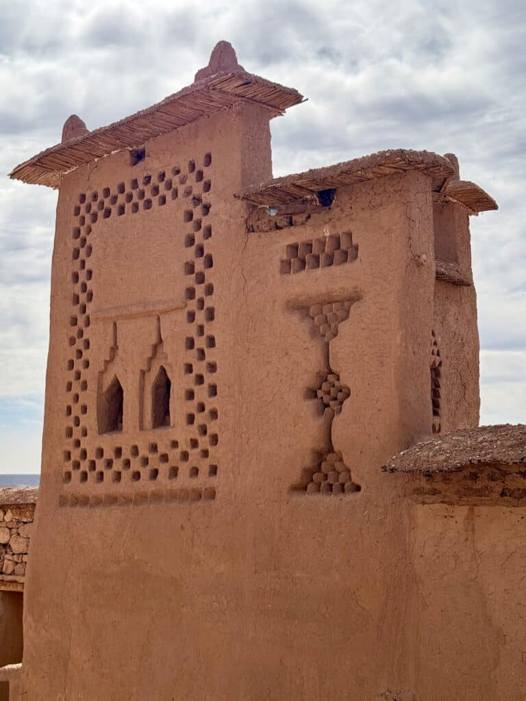 Torre de adobe en Marruecos con relieves decorativos geométricos en sus fachadas, perteneciente a una construcción tradicional amazigh.