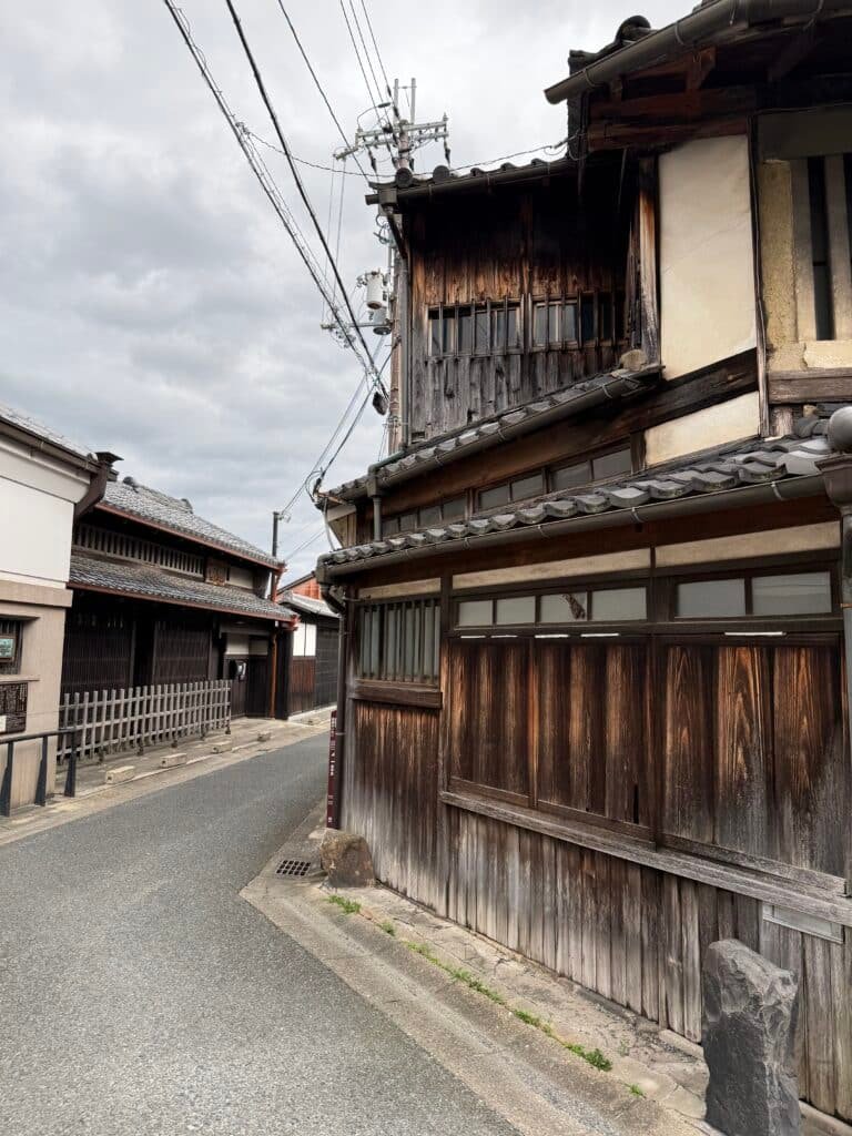 Calle histórica japonesa con fachadas de madera y casas tradicionales.